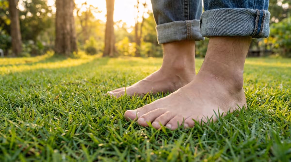 Person standing barefoot on grass practicing grounding technique during energy shift
