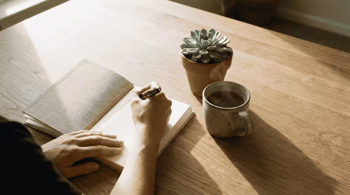 A person writing intentions in a manifestation journal while working on energy alignment for manifestation.