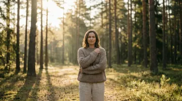 Woman setting healthy boundaries after narcissistic abuse, standing confidently with arms crossed in peaceful setting