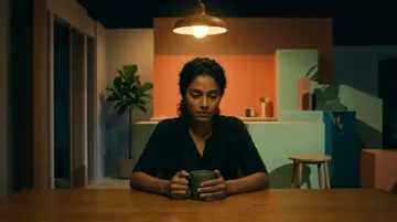 Woman sitting alone at night, hands around a cup, deep in thought about a painful relationship from trauma bonding