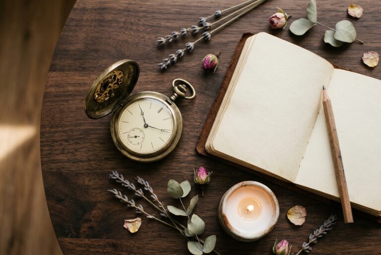 angel number meanings. Brass pocket watch and an open notebook on a wooden table.
