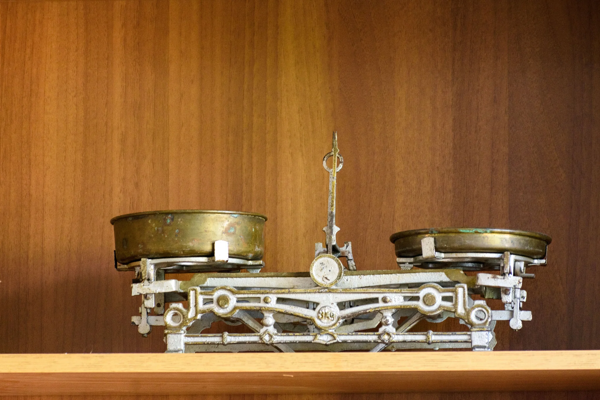 An antique brass balance scale with two pans.